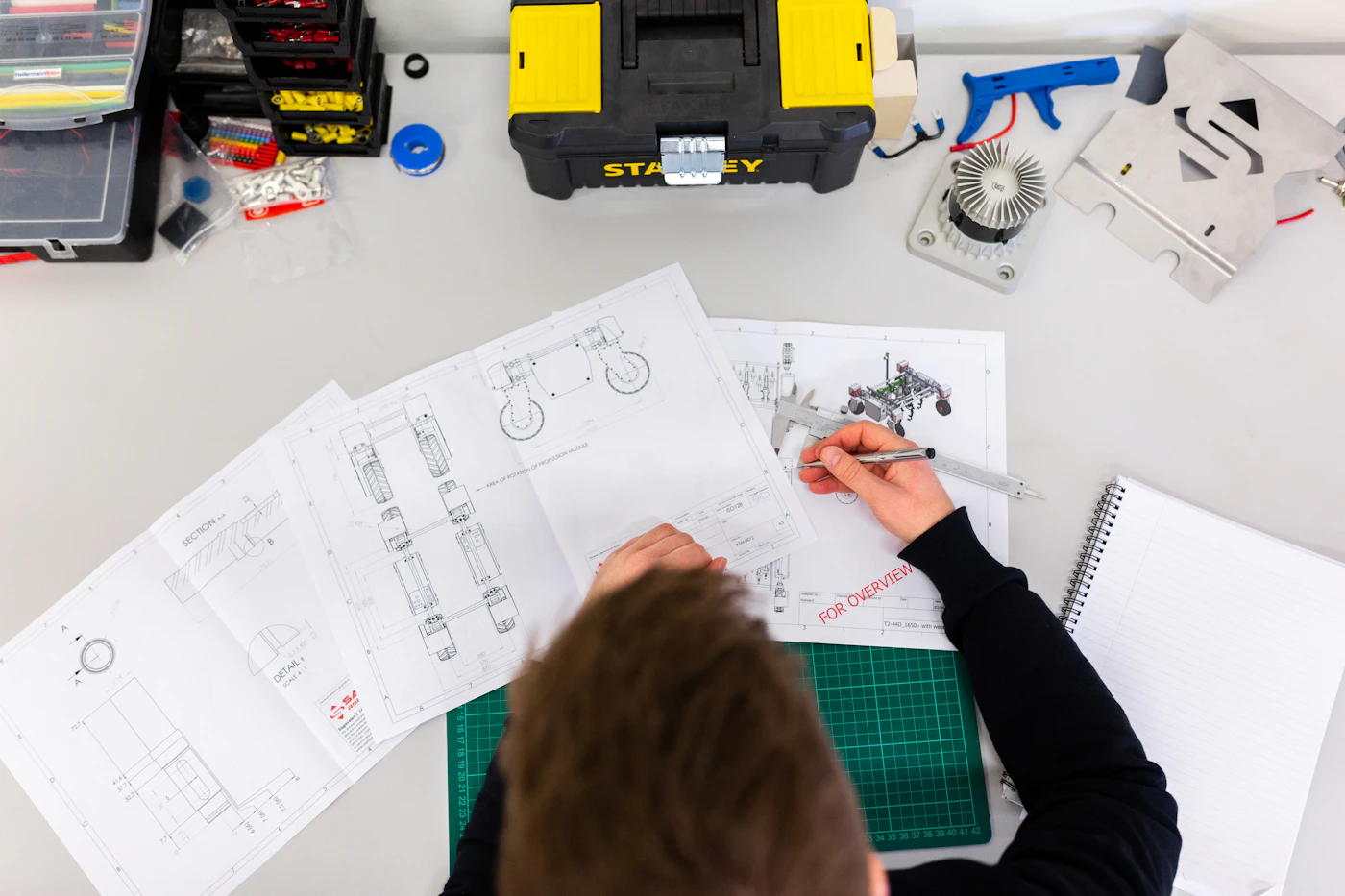 Tecnico al lavoro su disegni tecnici di componenti meccanici in ufficio tecnico