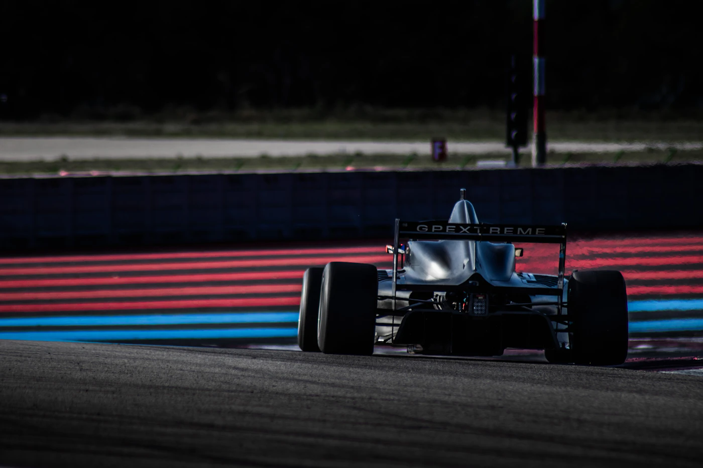 Auto da corsa nera in curva su un circuito: nel motorsport ogni chilo in meno vale decimi sul giro